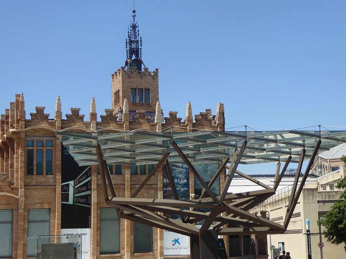 De voorgevel van het CaixaForum Barcelona, de vroegere fabriek Casaramona van Puig i Cadafalch, met de moderne glazen ingangsluifel