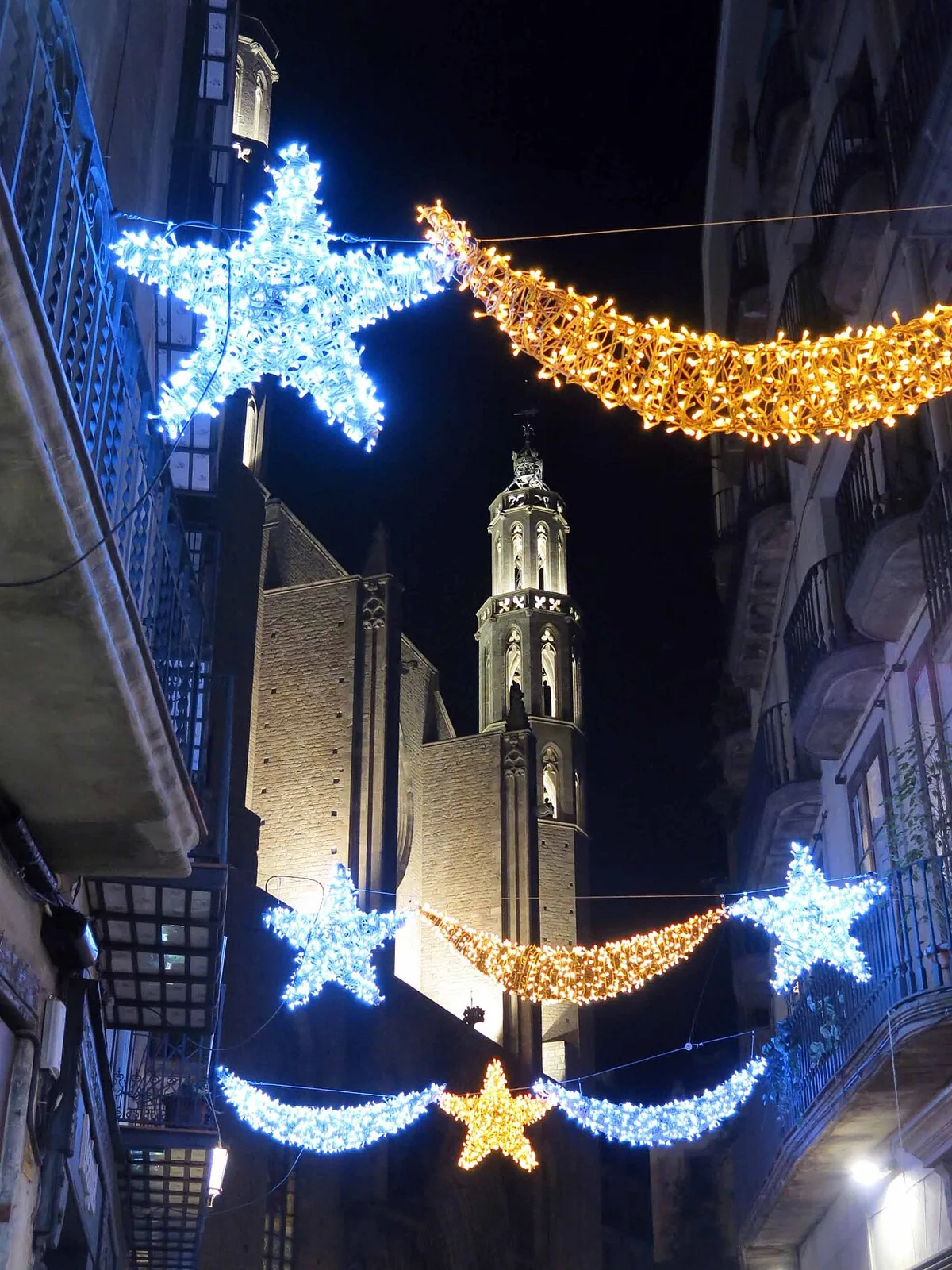 De toren van de Basílica de Santa Maria del Mar verlicht met kerstverlichting in de straten van El Born, Barcelona